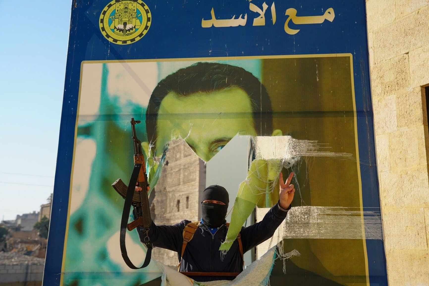 A rebel in Aleppo near a torn poster of Syrian President Bashar al-Assad, Nov. 30, 2024.