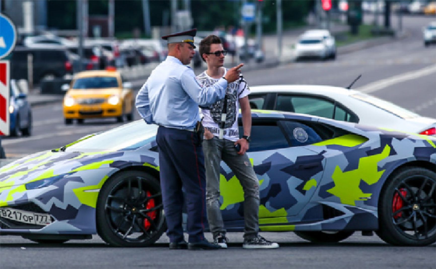 Максим Якубец разговаривает с полицейским на фоне своей Lamborghini с номером «ВОР»